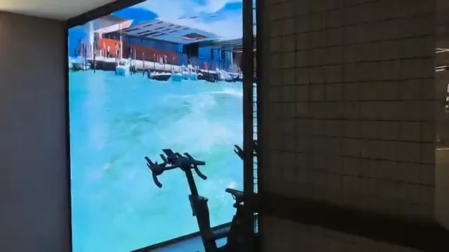 Bicicleta de spinning em frente ao painel com cenário de canal